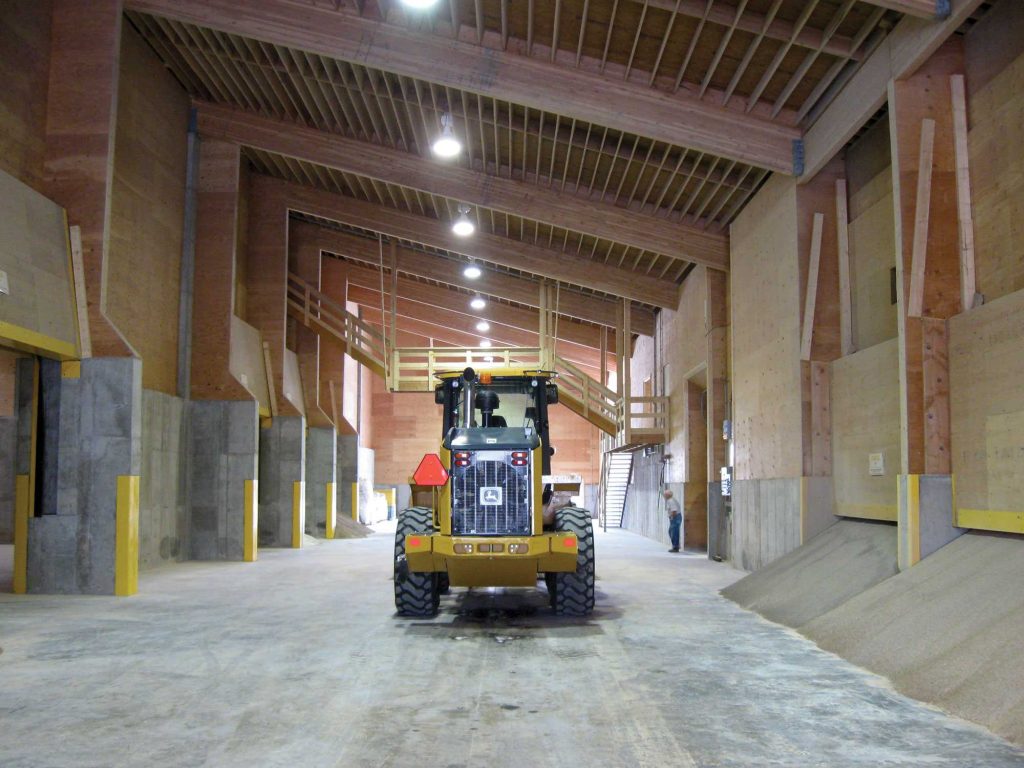 The inside of the dry fertilizer building at Cooperative Elevator features multiple bays for different products and a high sloped ceiling.