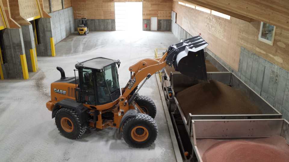 An employee moves dry fertilizer into a blending hopper.