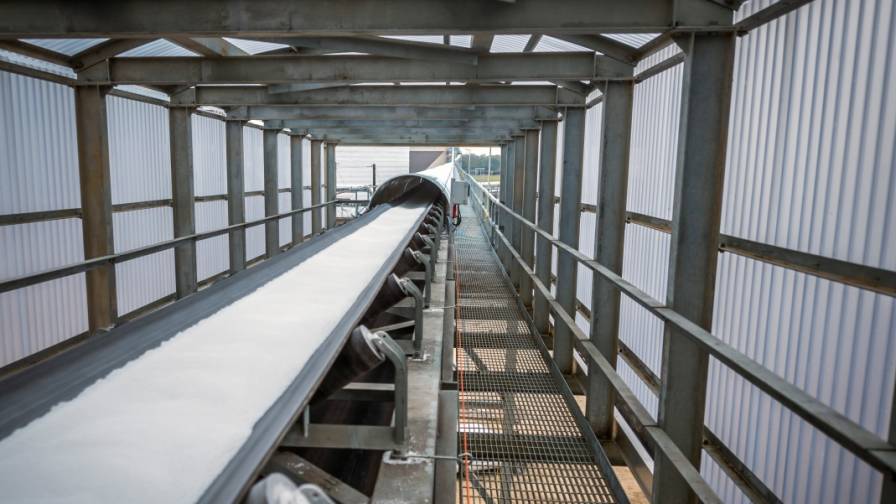 Fertilizer moves on a conveyor belt at a facility.